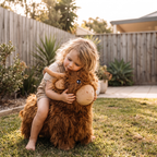 Child hugging Hamish the Highland Cow plush toy